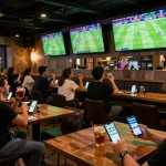 Fans using cakhiatv for live soccer betting in a lively sports bar atmosphere